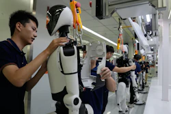 Technicians assemble and test a white humanoid robot in a laboratory facility