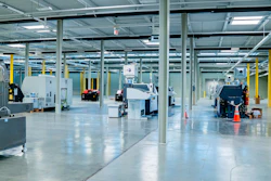 Spacious industrial manufacturing facility with polished concrete floors, yellow support columns, and various machinery equipment