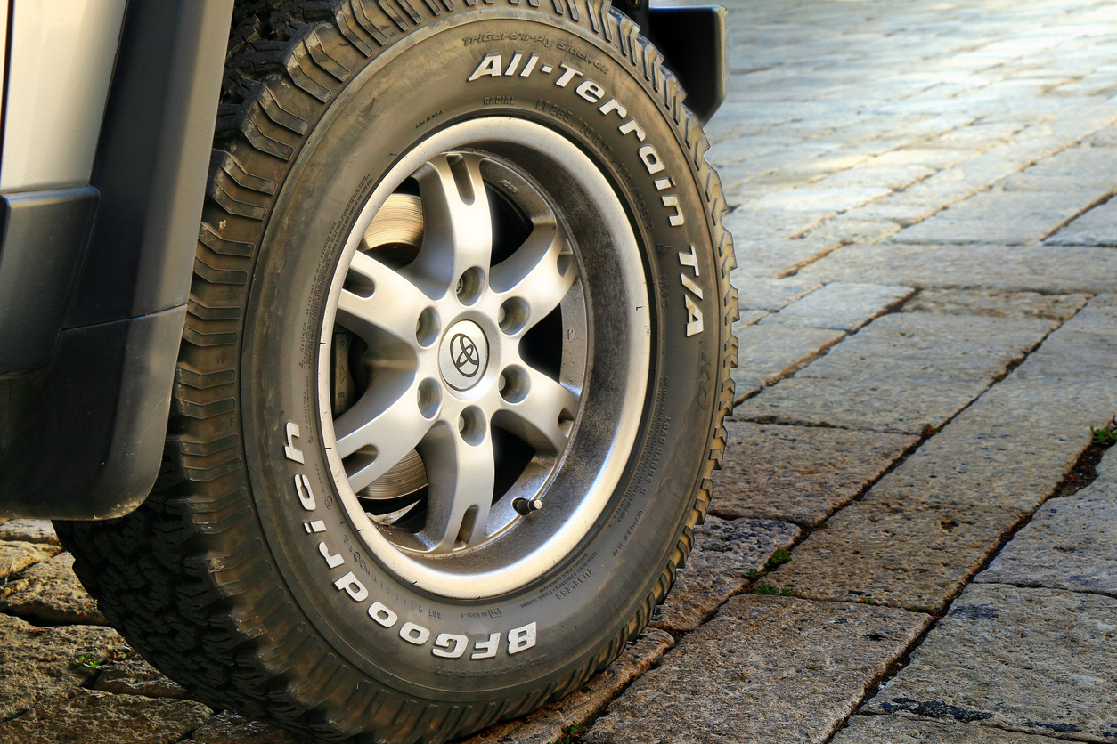 BFGoodrich all-terrain tire mounted on silver alloy wheel of parked vehicle