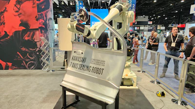 Kawasaki Pano Sealing Robot on display at an industrial trade show with visitors in background
