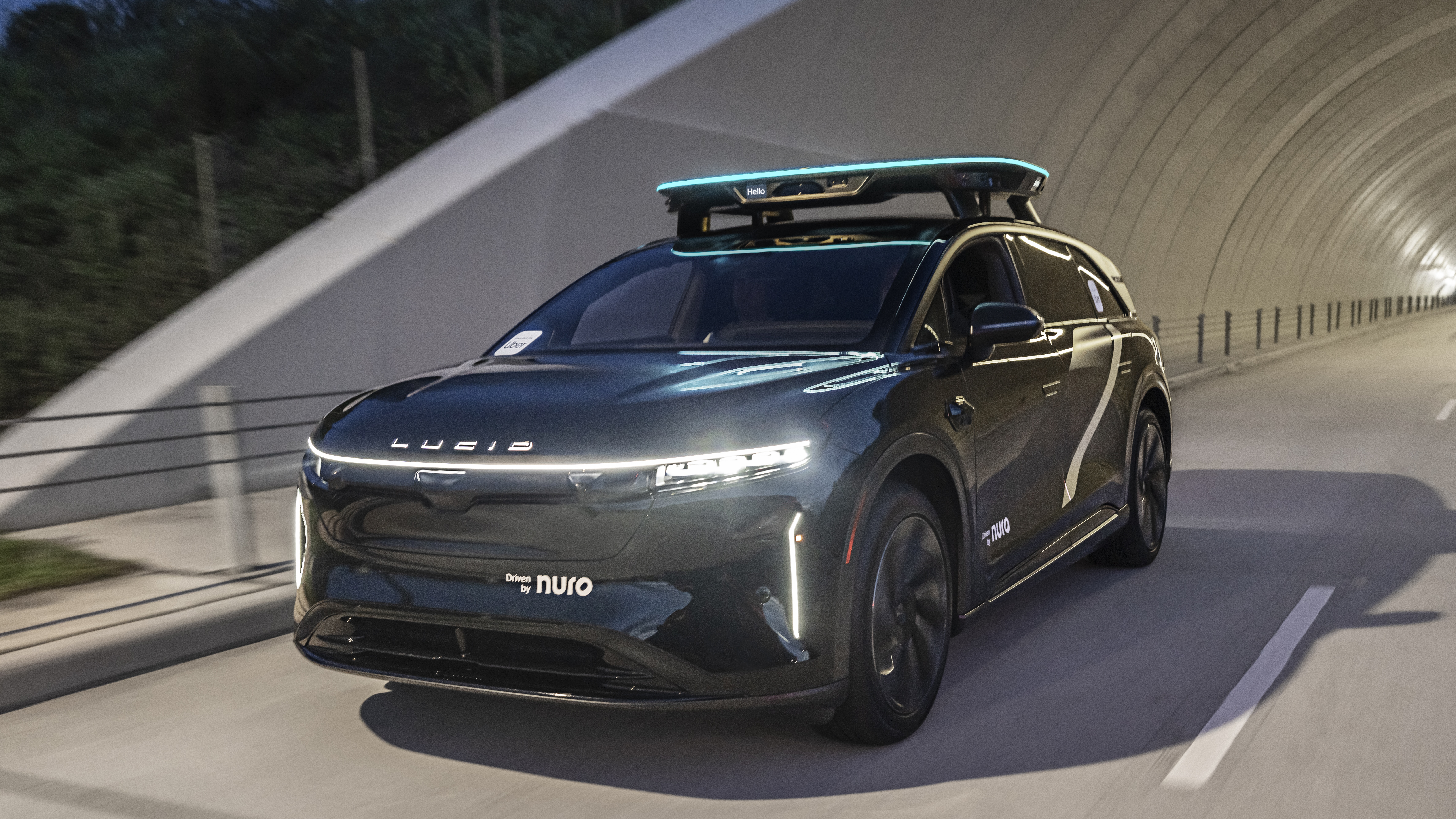 Dark gray Lucid Air electric SUV with roof rack driving through modern tunnel