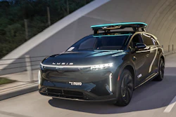 Dark gray Lucid Air electric SUV with roof rack driving through modern tunnel