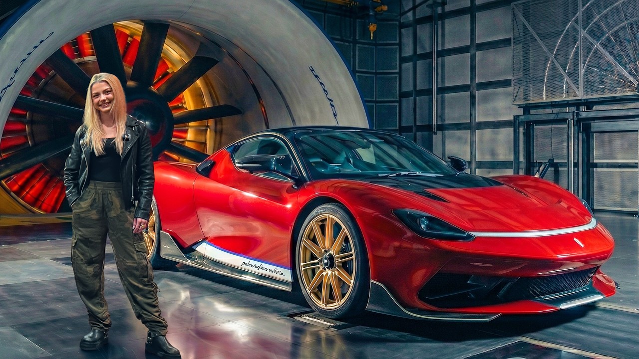 Woman in black leather jacket posing next to red sports car with gold wheels in modern industrial garage