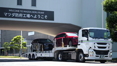 Mazda Hofu Plant entrance with white car carrier truck transporting red and black vehicles