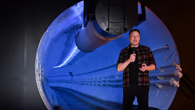 Man in plaid shirt presenting SpaceX Starship spacecraft model illuminated in blue light