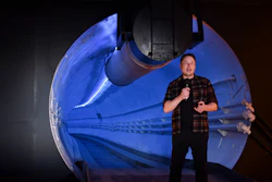 Man in plaid shirt presenting SpaceX Starship spacecraft model illuminated in blue light