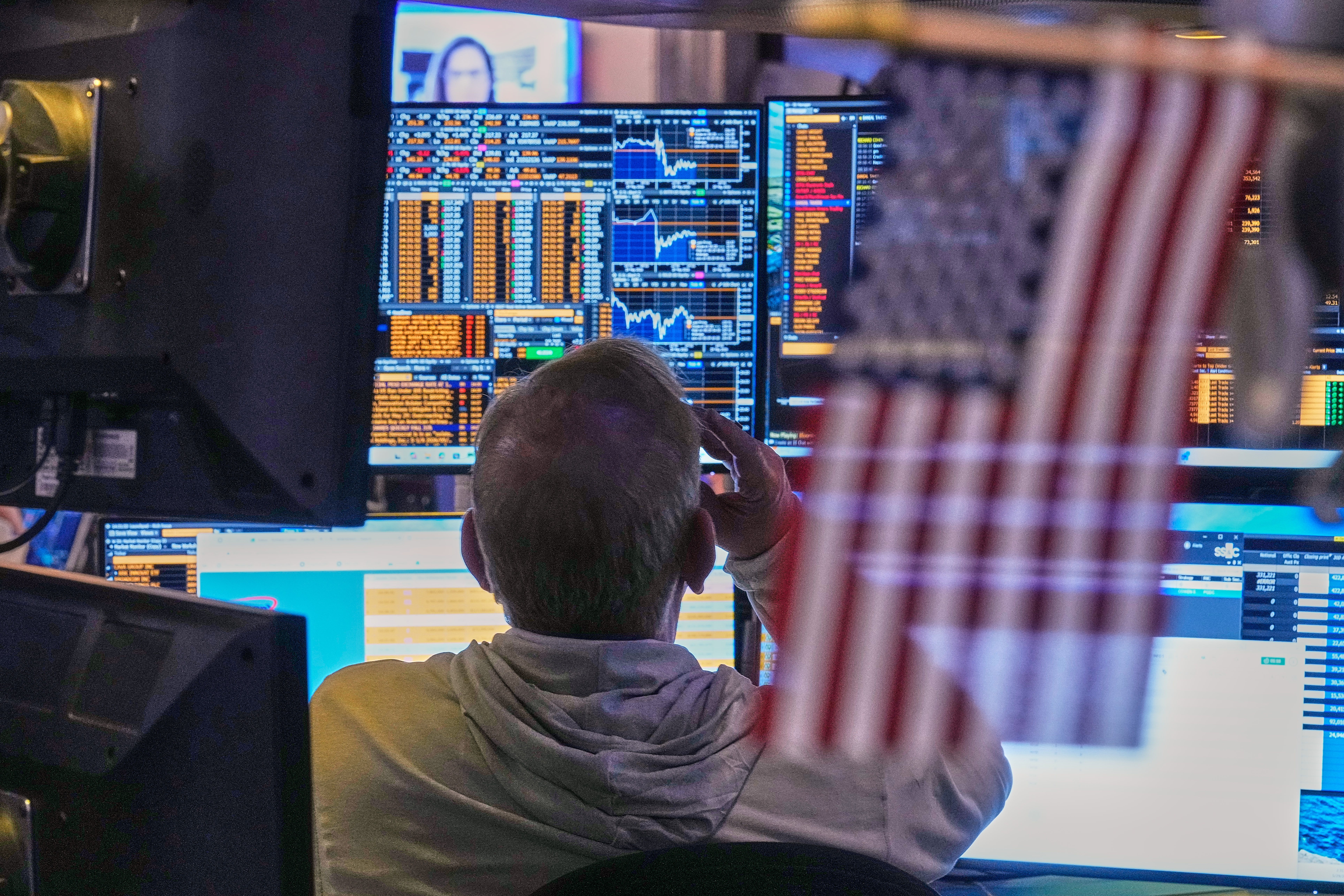 Trader monitoring financial markets on multiple data screens displaying stock charts and trading information