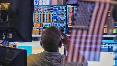 Trader monitoring financial markets on multiple data screens displaying stock charts and trading information