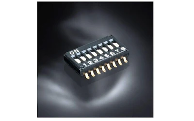 Black DIP switch module with 8 toggle switches and gold pin connectors on dark background