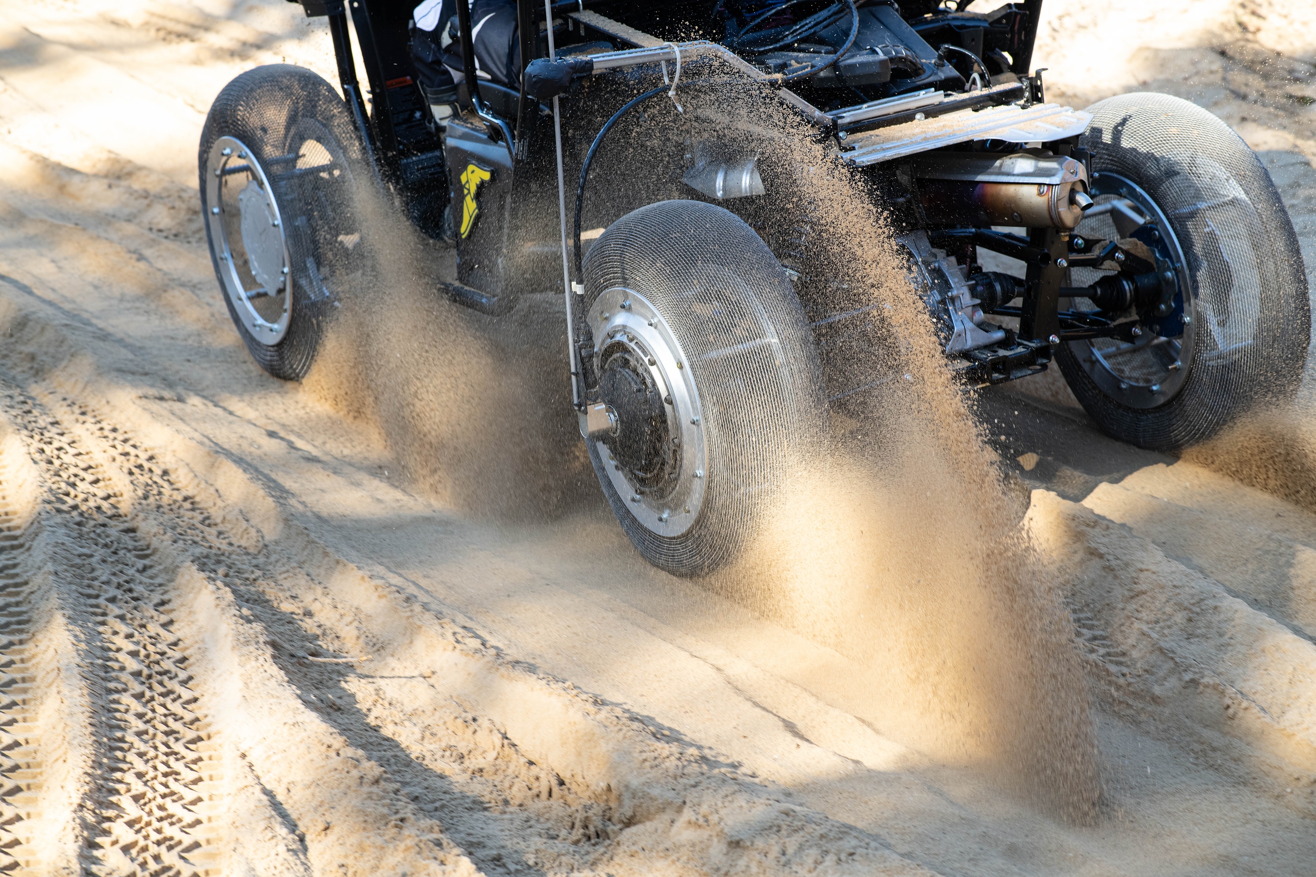 Vintage hot rod accelerating through sand with dramatic dust cloud billowing behind