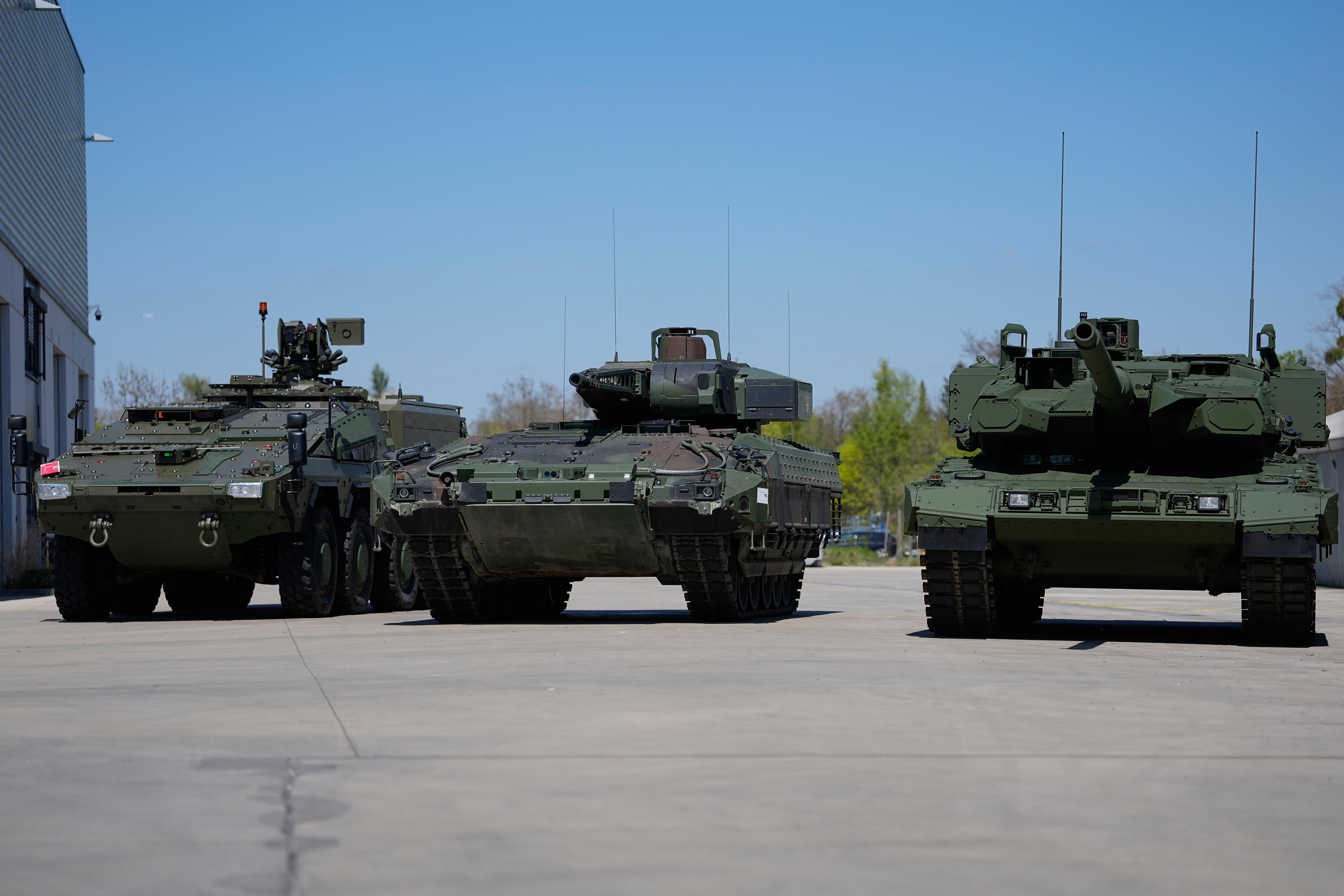 Three military armored personnel carriers lined up on concrete surface at military facility