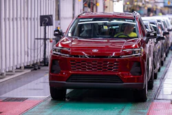 Red Toyota SUV on assembly line in manufacturing facility with quality control worker