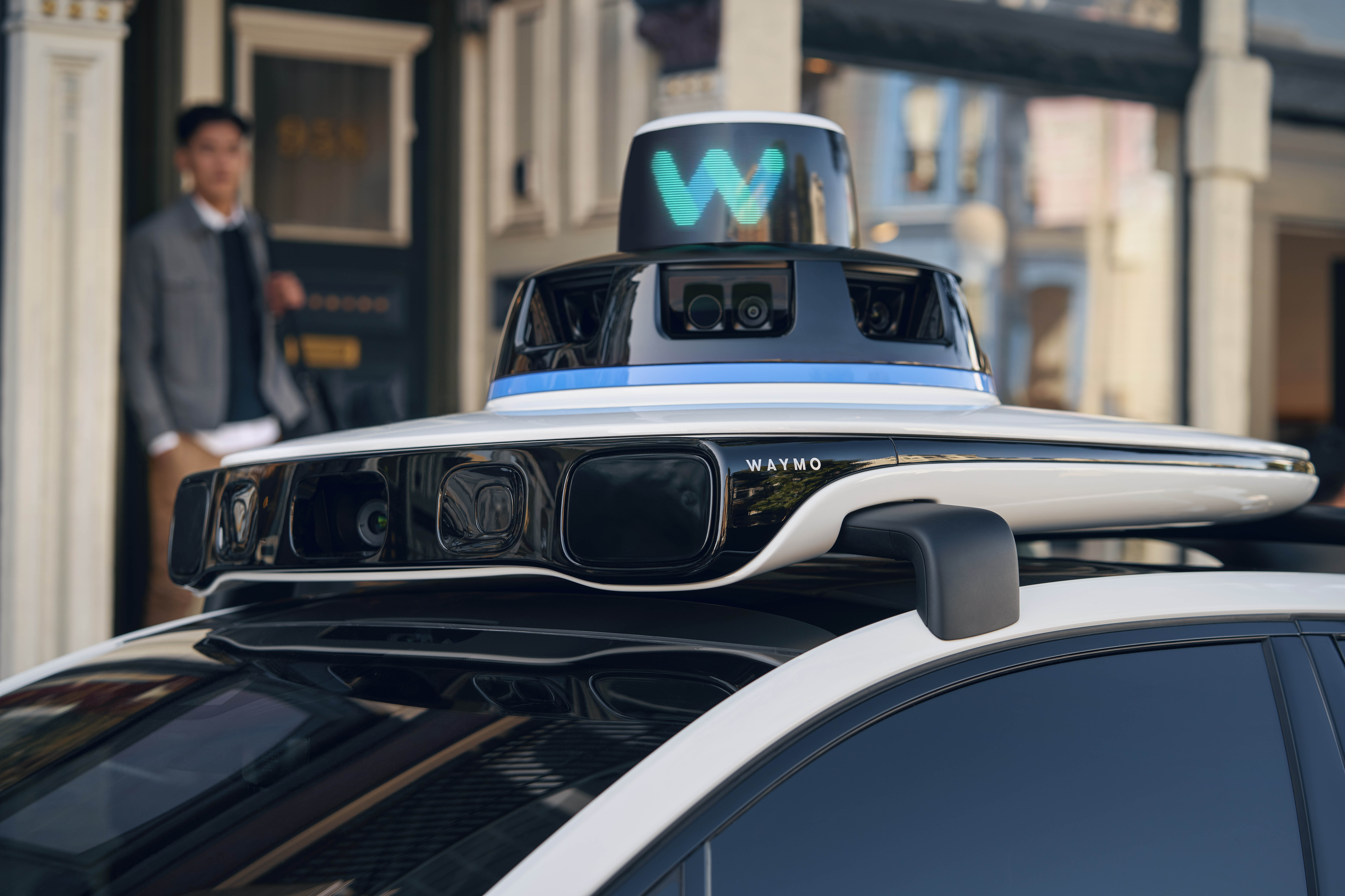 Waymo autonomous vehicle with sensor array and cyan logo displayed on rooftop equipment