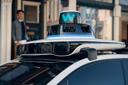 Waymo autonomous vehicle with sensor array and cyan logo displayed on rooftop equipment