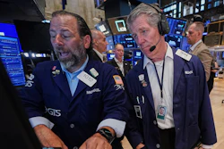 Stock exchange traders in navy blazers monitor market data on blue screens during trading session