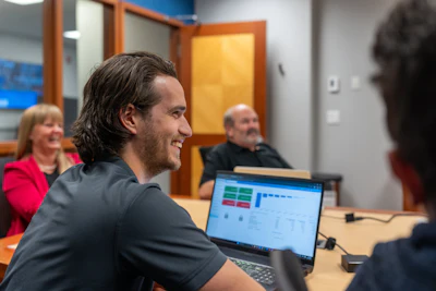 Professional team collaborating in office meeting with laptop displaying analytics dashboard