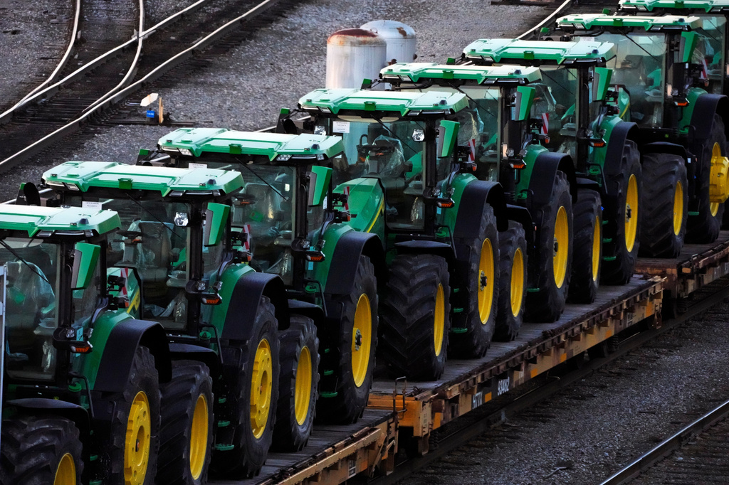 Row of green and yellow John Deere tractors loaded on a transport trailer