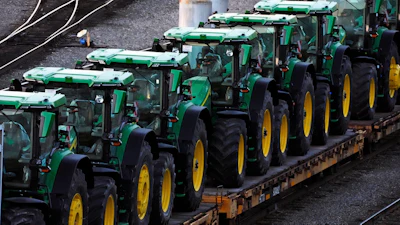 Row of green and yellow John Deere tractors loaded on a transport trailer