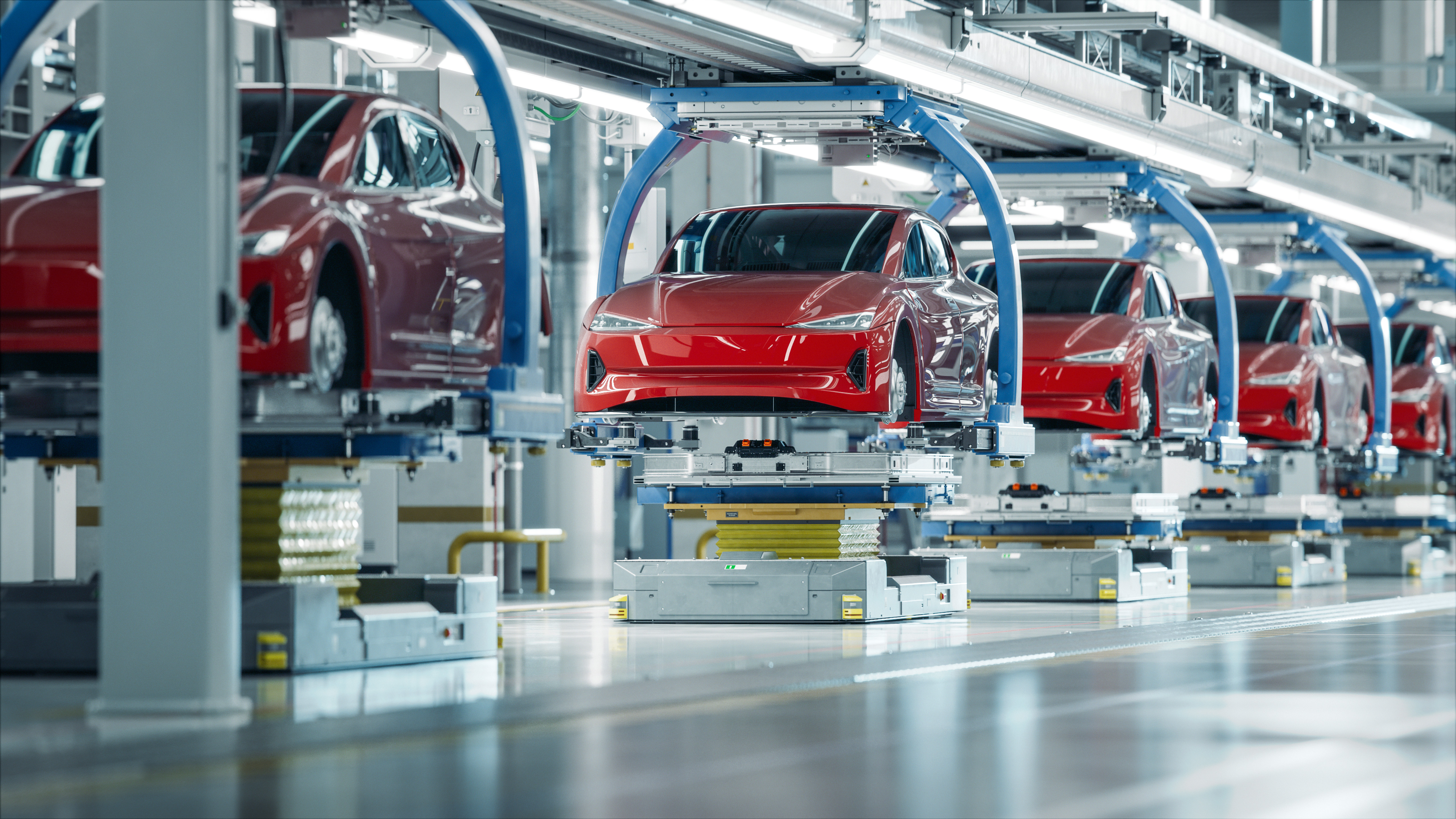Red Tesla vehicles on automated assembly line with blue robotic arms in modern manufacturing facility