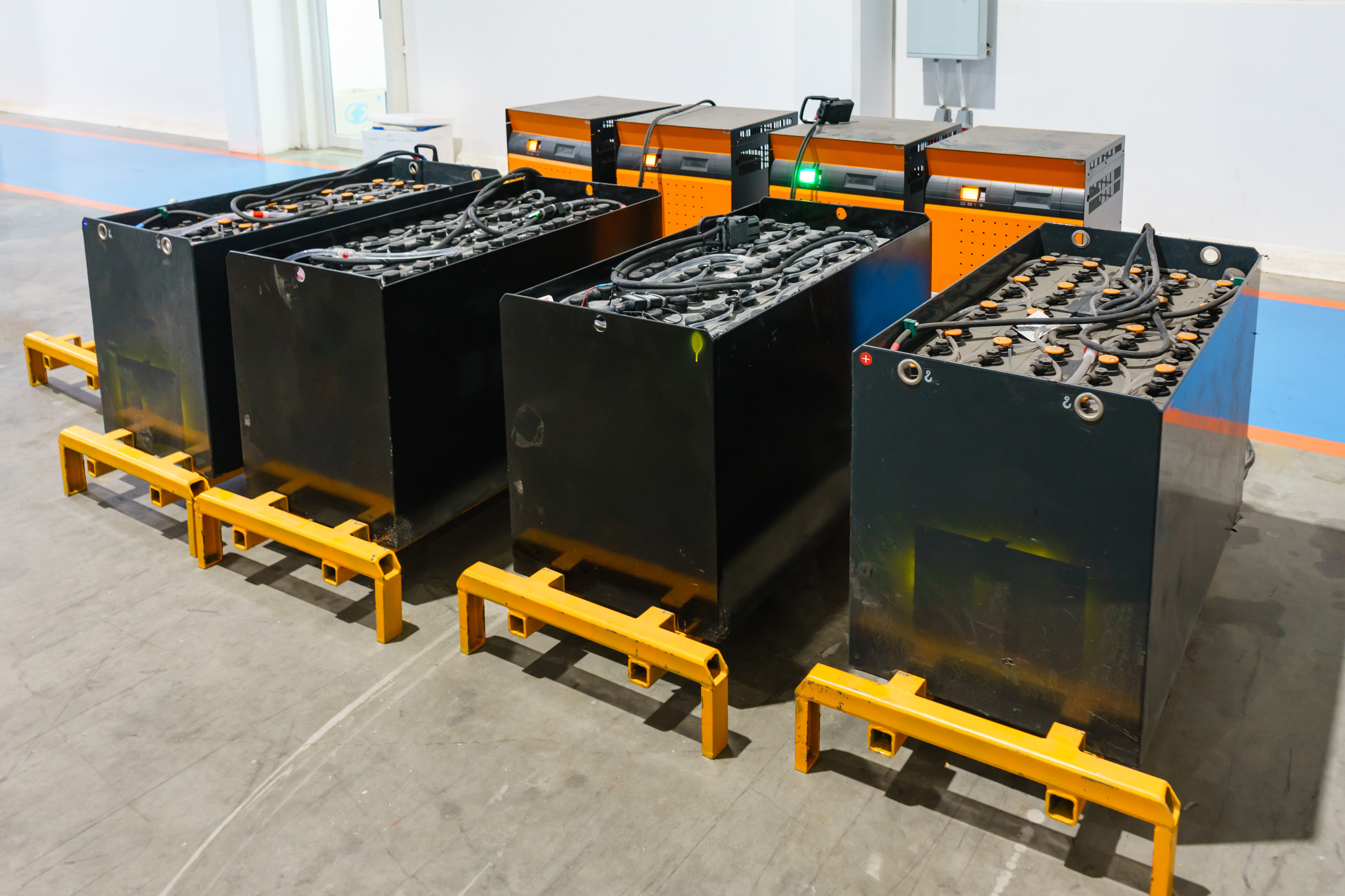 Industrial forklift battery units with yellow pallets arranged in warehouse facility