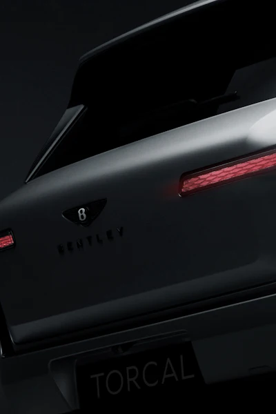 Rear view of dark Bentley luxury vehicle with illuminated red taillights and chrome trim details