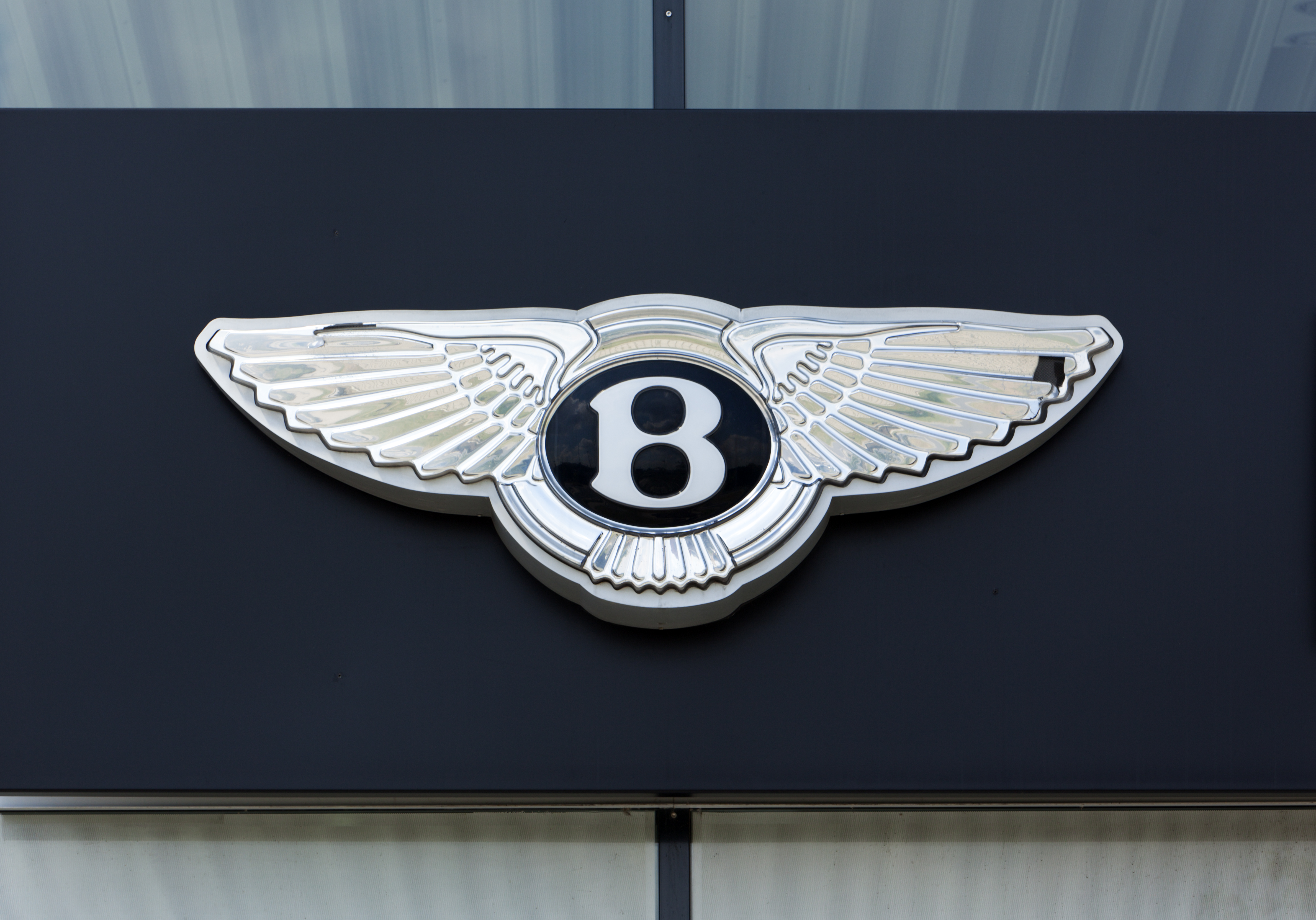 Bentley Motors winged 'B' emblem mounted on dark exterior surface