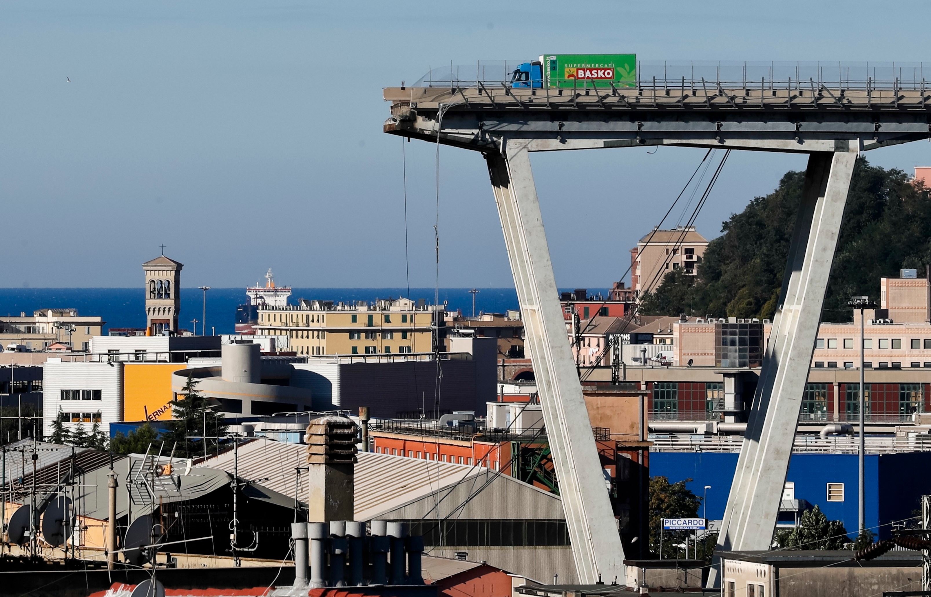 Cargo truck on elevated bridge structure above port city with Mediterranean sea and historic architecture visible