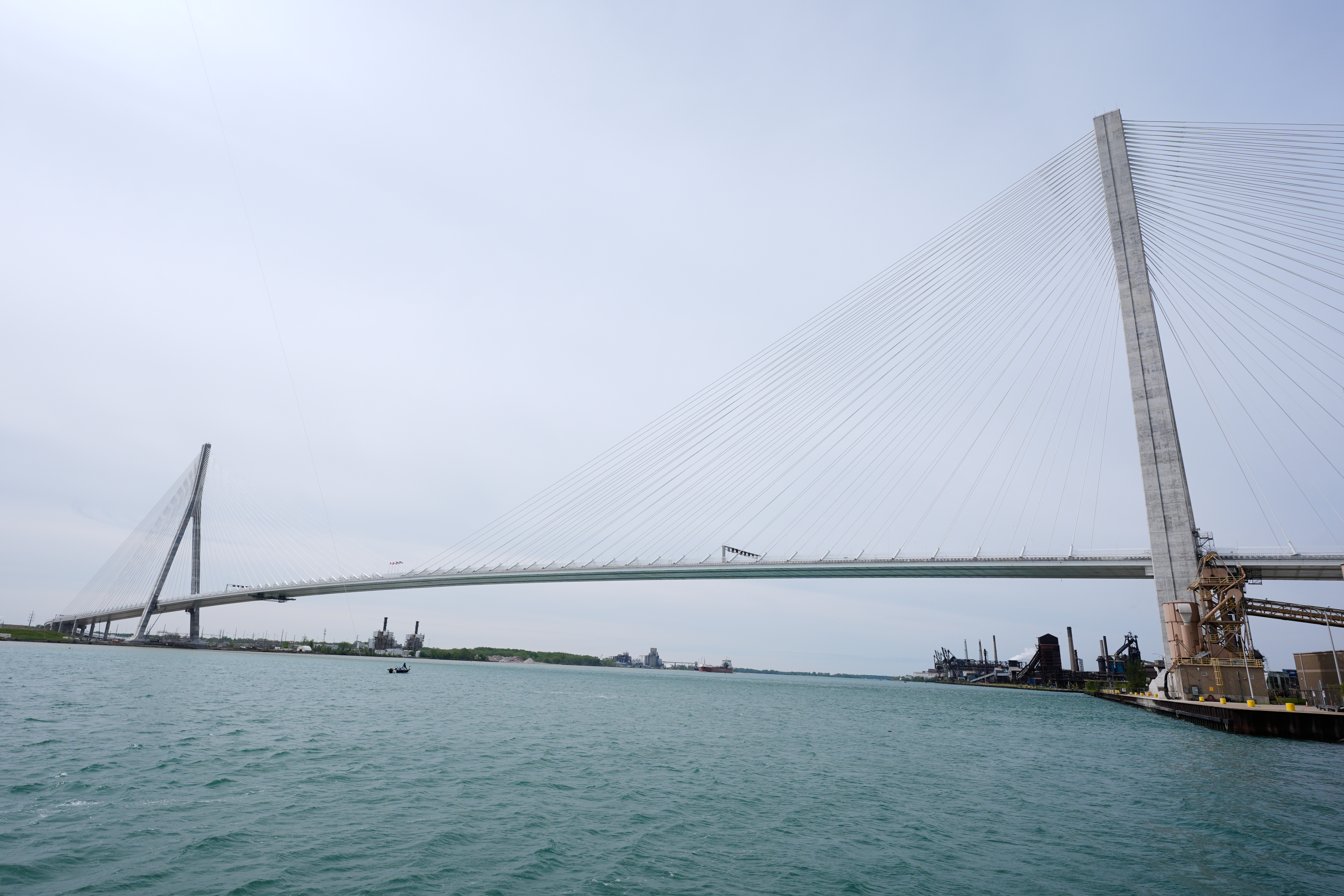 Vasco da Gama Bridge spanning turquoise waters under overcast sky with industrial port visible