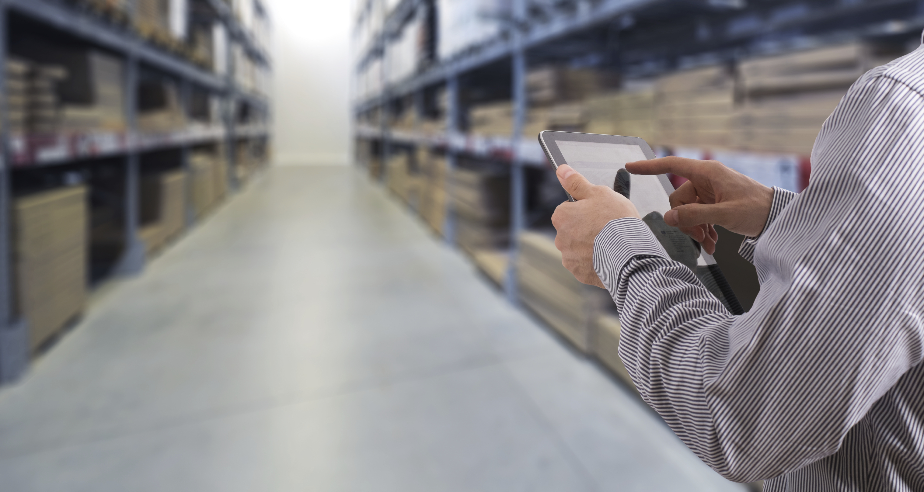 Warehouse worker using tablet to check inventory among storage shelves