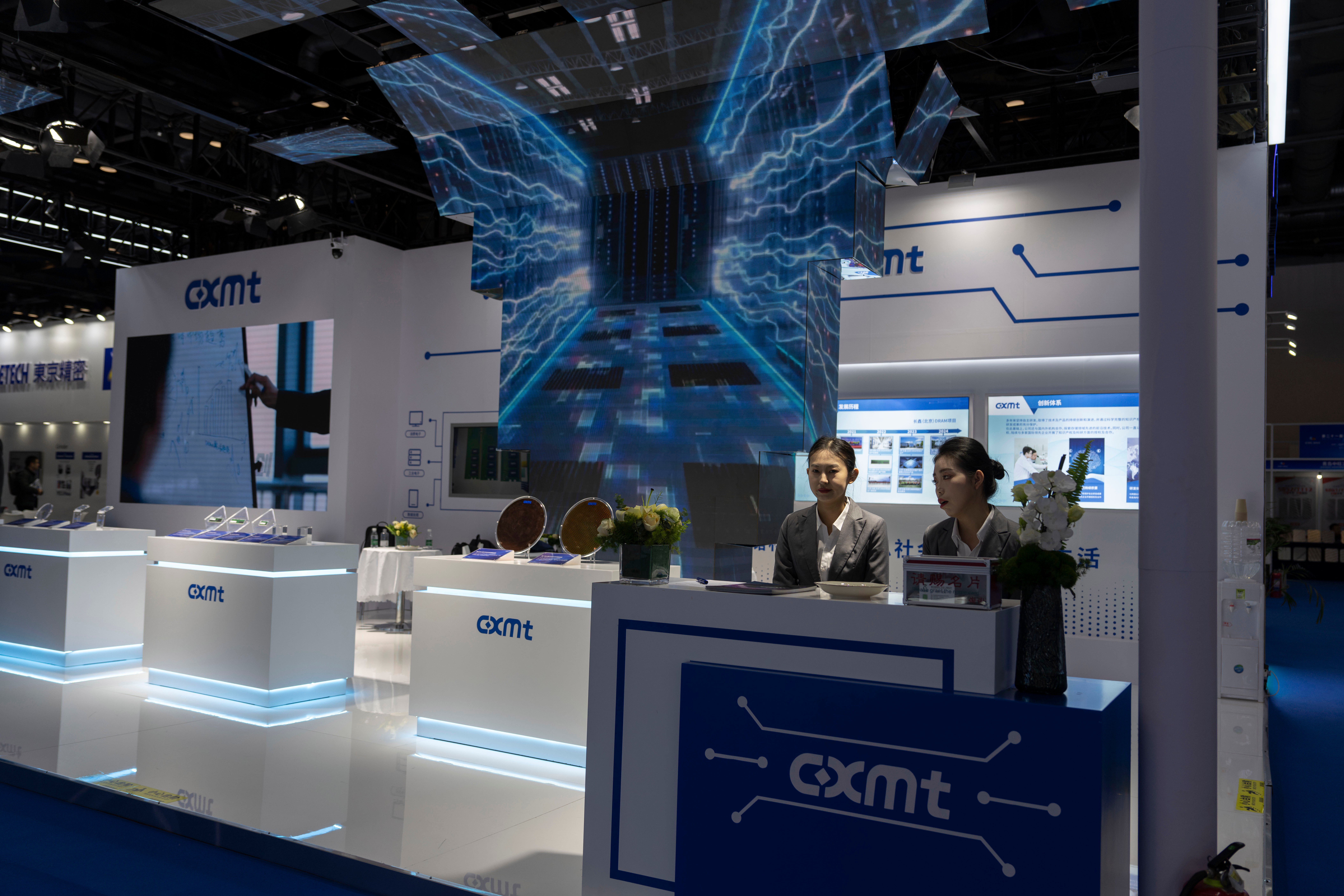 CXMT trade show booth with blue digital display, reception desk, and staff at technology exhibition