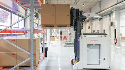 ABB warehouse facility with stacked cardboard boxes, automated robotic arm, and industrial equipment