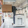 ABB warehouse facility with stacked cardboard boxes, automated robotic arm, and industrial equipment