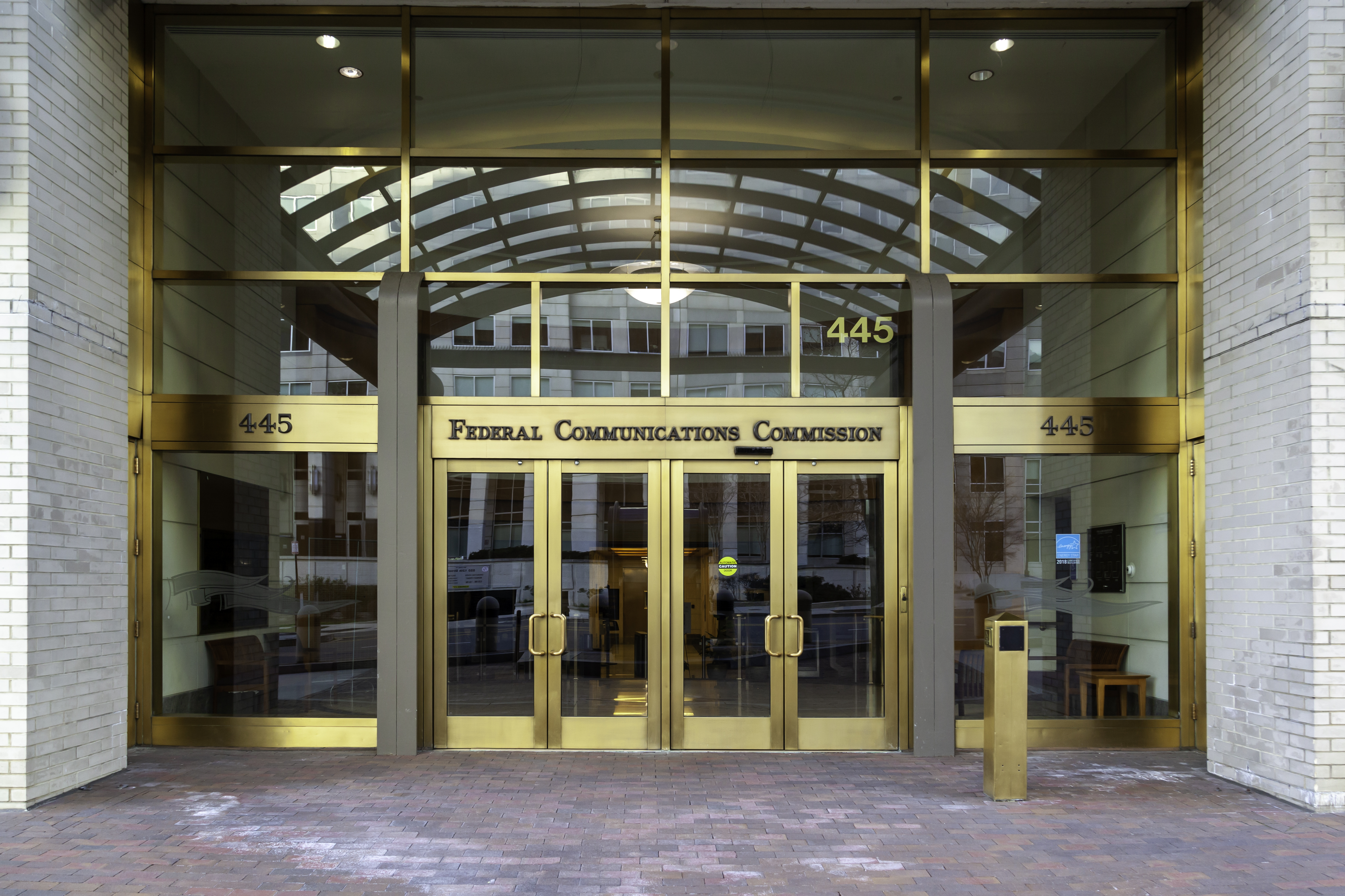 FCC Federal Communications Commission building entrance with gold-framed glass doors and address 445