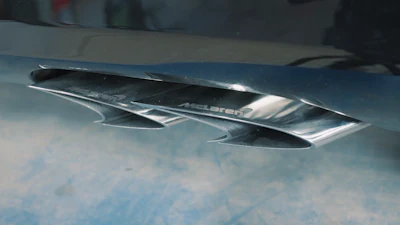 McLaren exhaust pipes with chrome badging on blue car hood