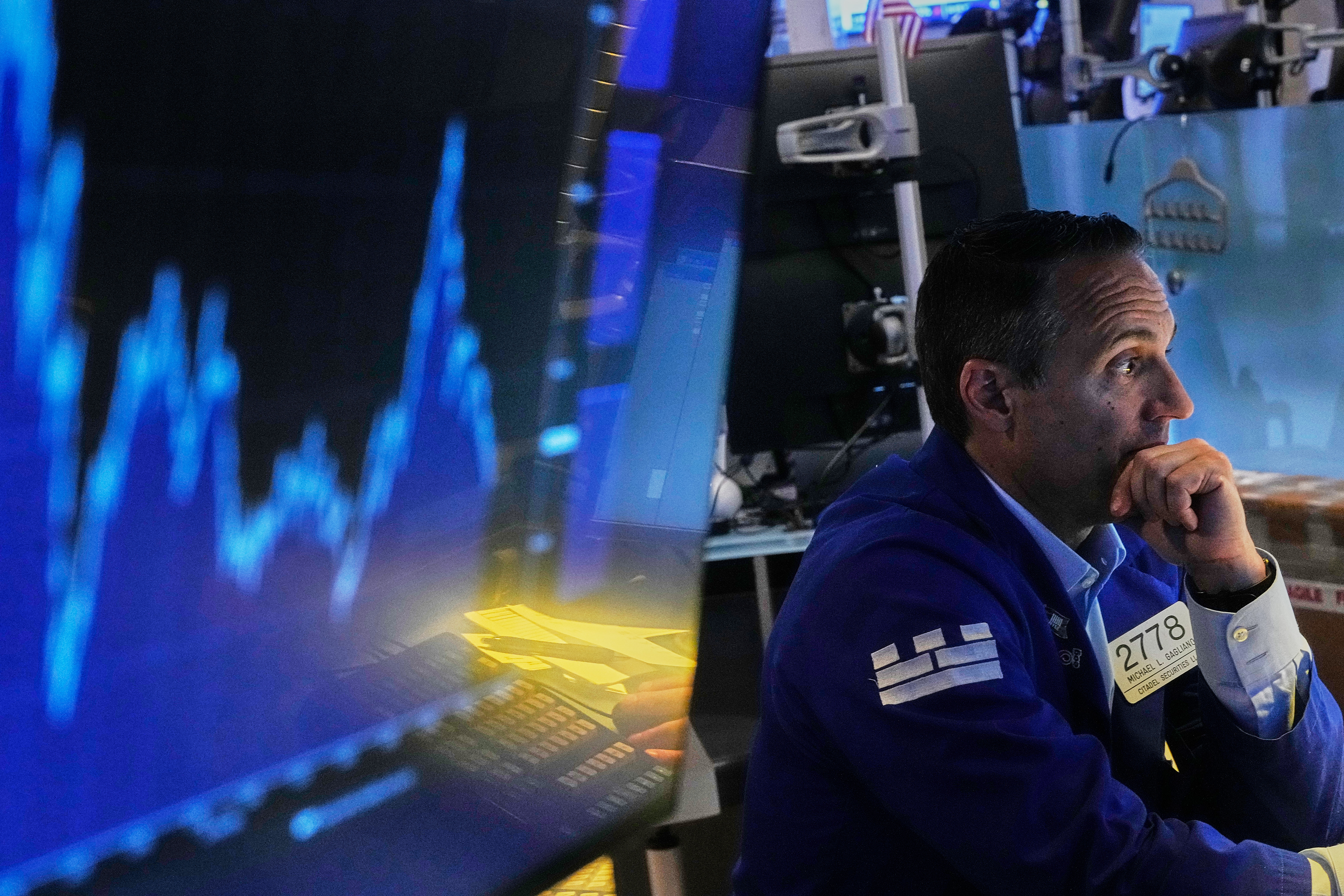 Stock trader in navy jacket monitoring financial charts on blue-lit trading floor screens