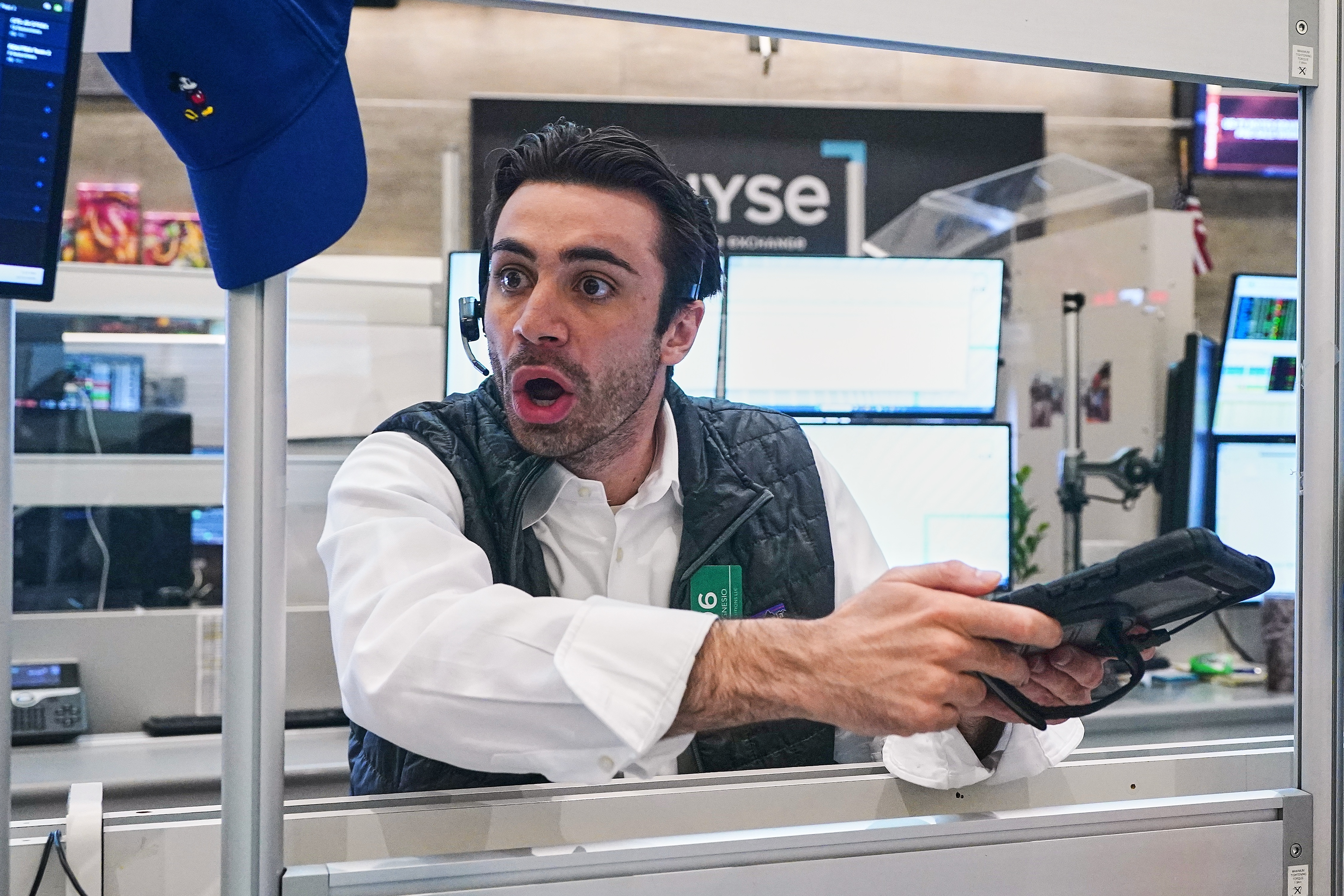 Man in white shirt and black vest holding empty wallet with surprised expression in trading floor office