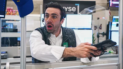 Man in white shirt and black vest holding empty wallet with surprised expression in trading floor office