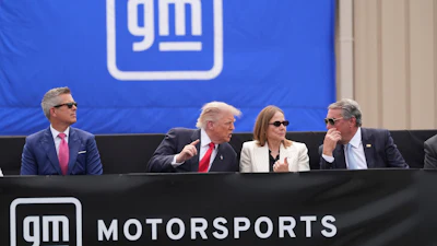 Four executives seated at a GM Motorsports branded podium during a corporate event