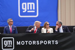 Four executives seated at a GM Motorsports branded podium during a corporate event