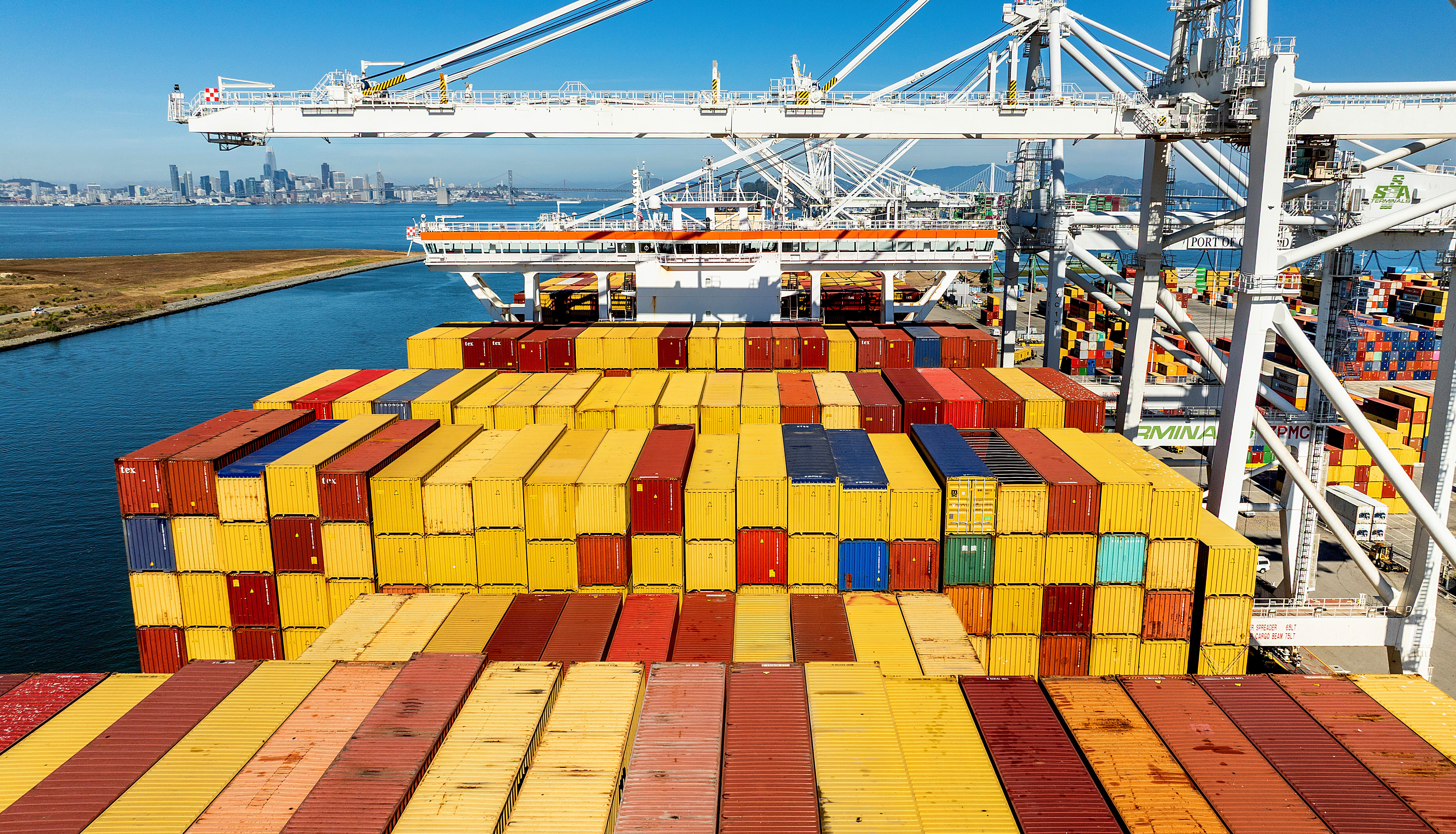 Colorful shipping containers stacked on cargo ship at busy port terminal with cranes and equipment