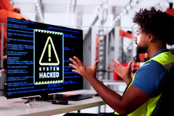 Factory worker in safety vest reacting to system hacked warning on computer monitor in industrial facility