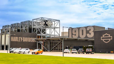 Harley-Davidson facility with 1903 establishment date, featuring industrial architecture, motorcycles parked outside, and the iconic shield logo on brown metal building.