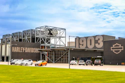 Harley-Davidson facility with 1903 establishment date, featuring industrial architecture, motorcycles parked outside, and the iconic shield logo on brown metal building.