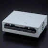 White metal industrial enclosure with black front panel, ventilation holes, and mounting fasteners on dark background