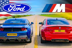 Blue Ford Mustang and red BMW M4 sports cars facing each other on a divided highway with American and German flags