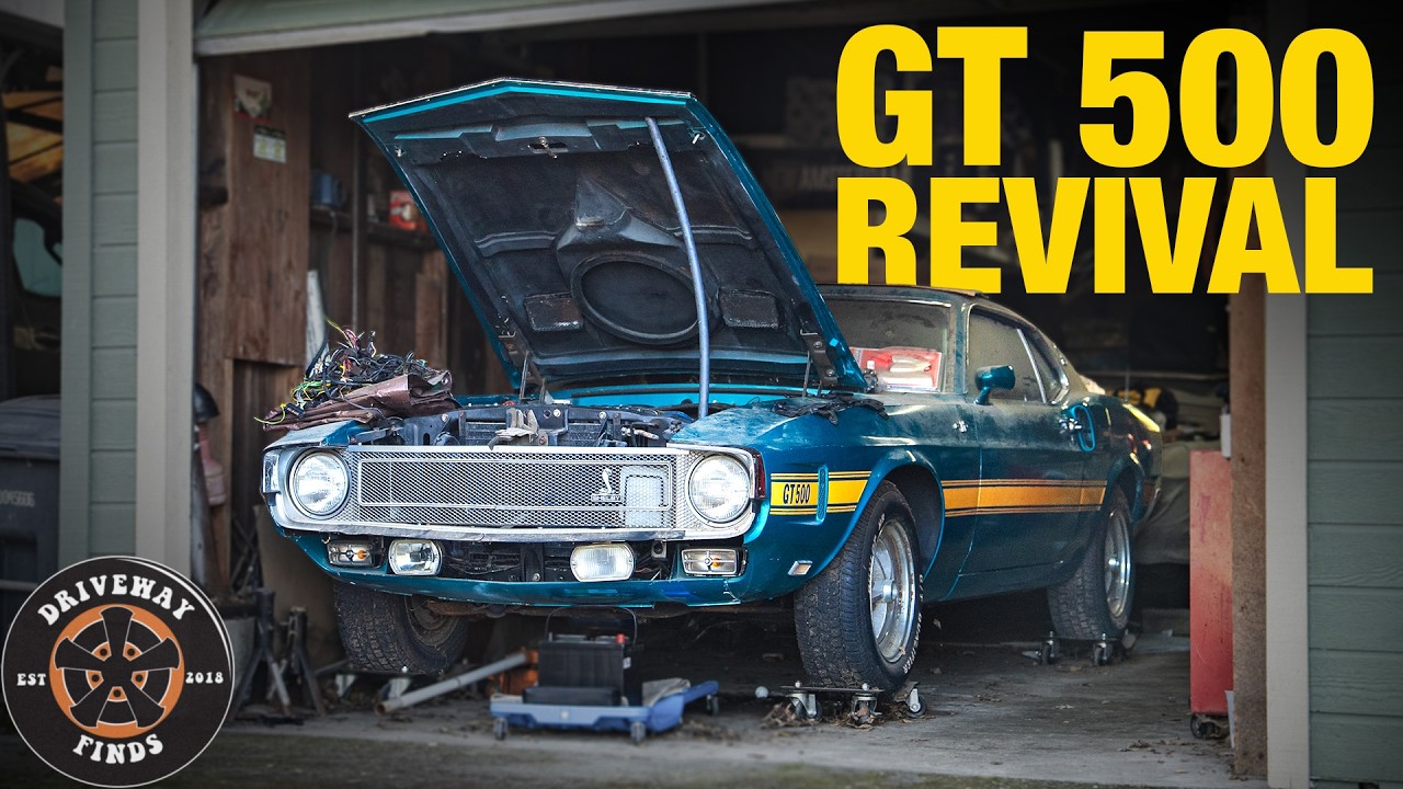 Blue Ford Mustang GT 500 undergoing restoration in garage with hood open and engine visible
