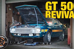 Blue Ford Mustang GT 500 undergoing restoration in garage with hood open and engine visible