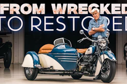 Restored blue and white motorcycle with sidecar and man in workshop setting with 'From Wrecked to Restored' text