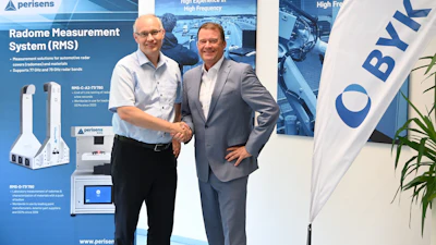 Two business professionals shaking hands at Perisens corporate event with Radome Measurement System product displays and branded banners
