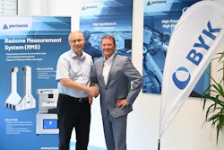 Two business professionals shaking hands at Perisens corporate event with Radome Measurement System product displays and branded banners